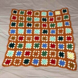 Crochet orange afghan with multicolored granny core squares